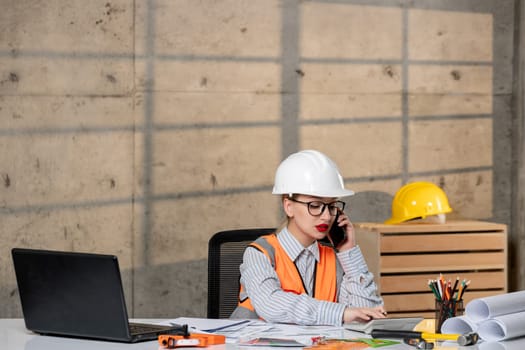 engineer in helmet and vest civil worker smart young cute blonde girl on phone call at work