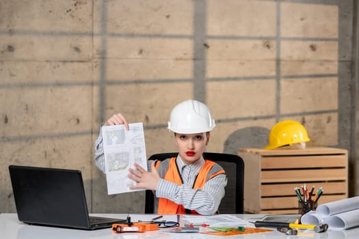 engineer in helmet and vest civil worker smart young cute blonde girl showing new plan