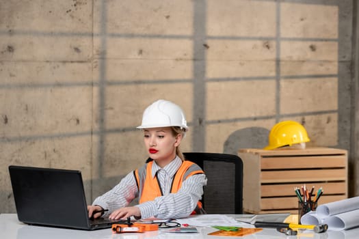 engineer in helmet and vest civil worker smart young cute blonde girl working on computer