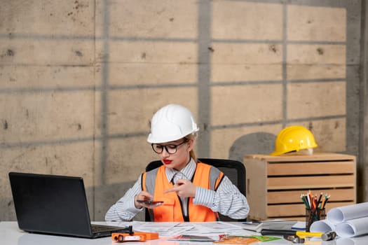 engineer in helmet and vest civil worker smart young cute blonde girl working on project