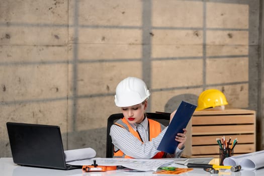 engineer in helmet and vest civil worker smart young cute blonde girl writing plan