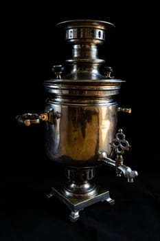 an old samovar isolated on a black background. Metal vessel for boiling water and making tea.Russian samovar