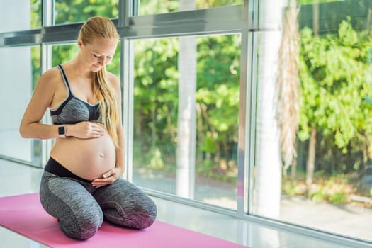 Young pregnant woman doing yoga exercises and meditating at home or yoga studio. Health care, mindfulness, relaxation and wellness concept.