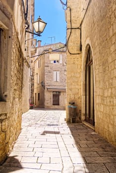 Narrow street with stone houses. Old houses and old narrow alley in Trogir, Croatia, Europe. Streets in old town.