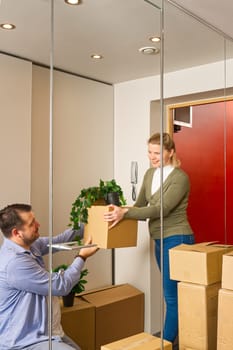 Happy couple moving in their new apartment carrying cardboard boxes. Young couple moving in new home. fun with cardboard boxes at moving day.