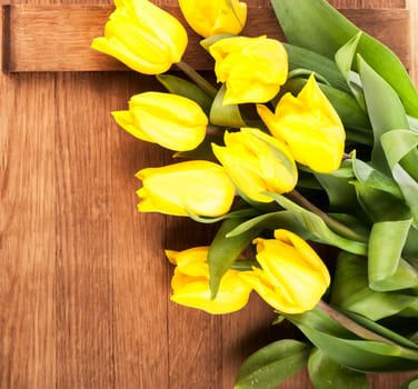 Bouquet of yellow tulips on wooden background