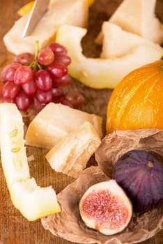 white wine, cheese, melon, grapes figs on a dark background