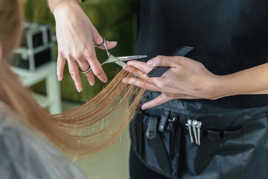Hairdresser cut hair of a blonde girl
