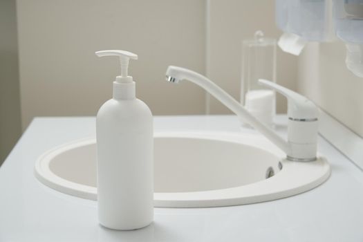 Faucet and liquid soap bottle on a sink background. High quality photo