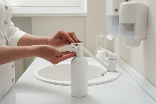 Cropped view of female hands pressing on soap bottle before washing hands