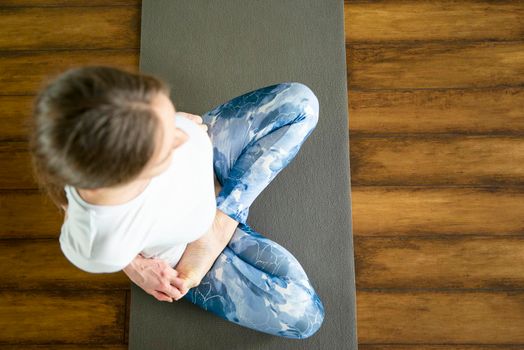 Health concept. Young attractive woman does yoga exercise in the gym against white wall