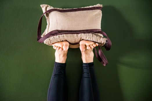 Young woman in yoga relaxing pose with legs up by a wall with heavy sand bags