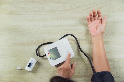 old woman with pressure gauge checking blood pressure level on the table