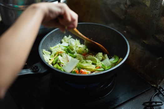 women cooking fried vegetables in the kitchen