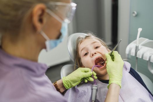 A cute little girl getting her teeth checked by dentist at dental clinic.