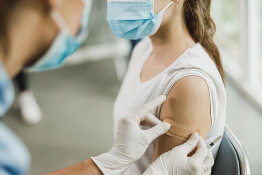 Close-up of a nurse applying a band aid to a cute teenager girl after receiving the Covid-19 vaccine.