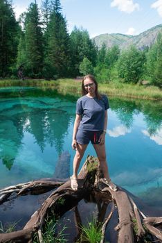 Woman at Beautiful Geyser lake with thermal springs that periodically throw blue clay and silt from the ground. Altai mountains, Russia