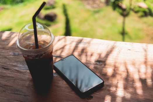 mobile phone and ice coffee put on the wood table