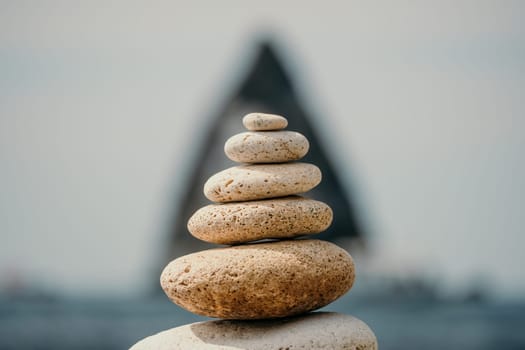 Pyramid stones on the seashore with warm sunset on the sea background. Happy holidays. Pebble beach, calm sea, travel destination. Concept of happy vacation on the sea, meditation, spa, calmness.