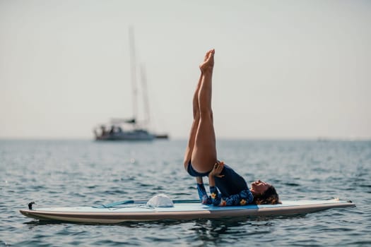 Woman sup yoga. Middle age sporty woman practising yoga pilates on paddle sup surfboard. Female stretching doing workout on sea water. Modern individual hipster outdoor summer sport activity