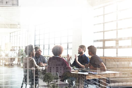 Multiple exposure shot of businesspeople having a meeting superimposed over a cityscape.