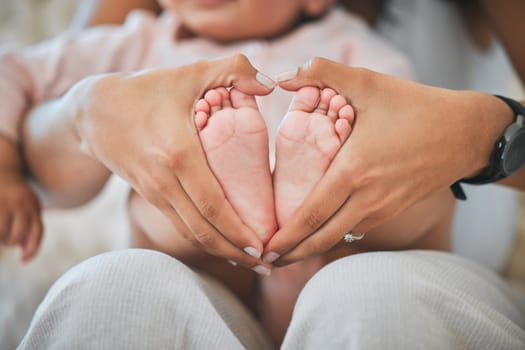 Baby, feet and hands in heart for love, care and nurture childhood development, growth and wellness of kids. Closeup, mother and hand shape around tiny foot of infant, newborn and child for support.