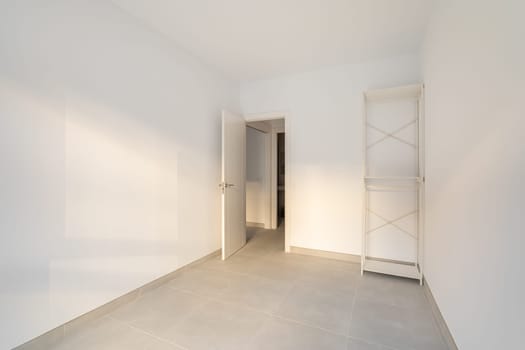 Narrow empty room with a closet and a door overlooking the corridor and other rooms. Concept of the apartment after the delivery of a new building or renovation. Copyspace.