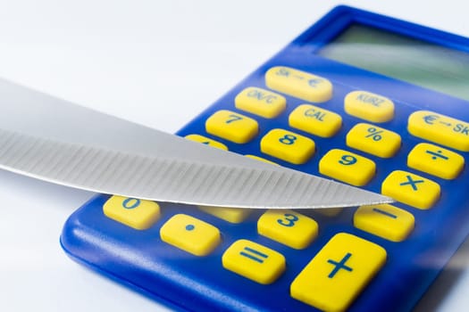 Knife blade placed on euro coin, calculator. Concept cut rates, money business, crime. Macro.