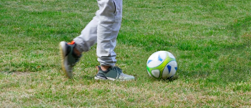 The legs of a boy who makes soccer exercises