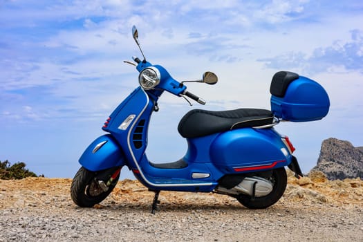 Blue motor scooter on coastal road with sea in background. High quality photo