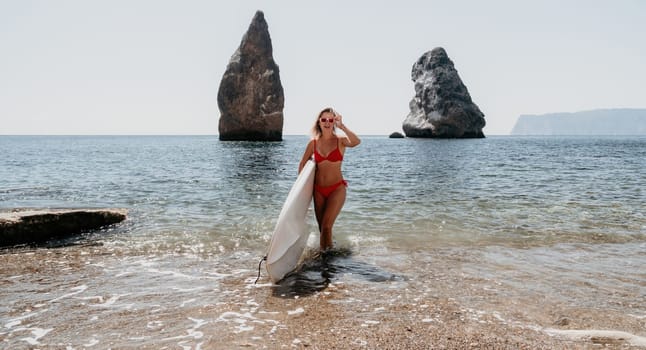 Close up shot of beautiful young caucasian woman with black hair and freckles looking at camera and smiling. Cute woman portrait in a pink bikini posing on a volcanic rock high above the sea