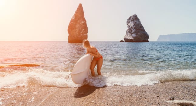 Close up shot of beautiful young caucasian woman with black hair and freckles looking at camera and smiling. Cute woman portrait in a pink bikini posing on a volcanic rock high above the sea