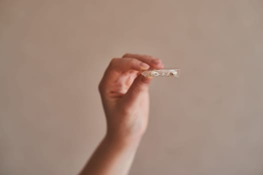 A girl holds a silicone mouthpiece orthodontic silicone trainer. Invisible braces aligner. Mobile orthodontic appliance for dental correction.