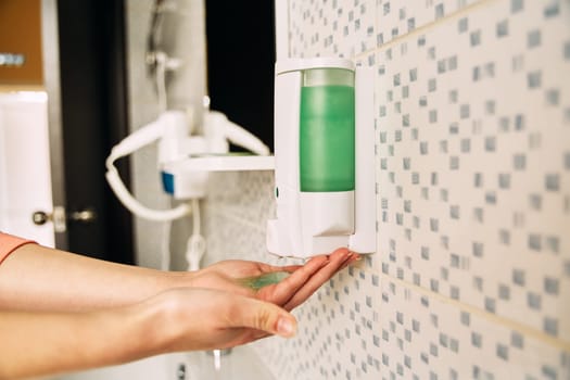 The girl squeezes the soap from the dispenser. Girl washes hands with soap for the prevention of viral diseases