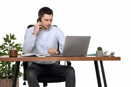 Successful happy businessman working with laptop and having phone conversation with client