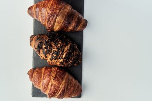 three croissants on a black tray top view. High-quality photo