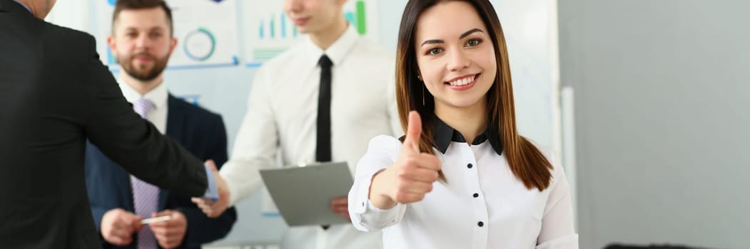 Happy businesswoman feels confident in team and holds thumbs up. Successful business team concept