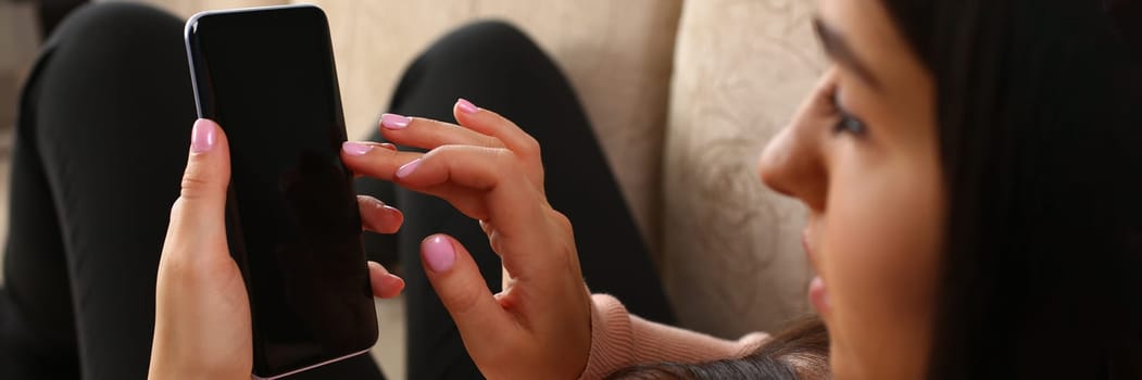 Woman lies on sofa and holds smartphone. Chatting correspondence and mobile applications concept