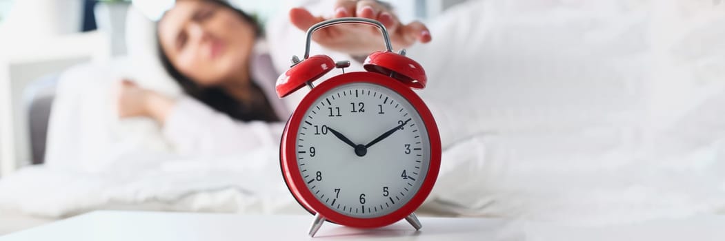 Dissatisfied woman turns off the alarm clock in bed. Insomnia stress and late waking up