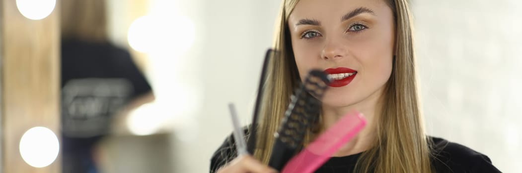 Portrait of woman hairdresser holding combs and scissors. Beauty salon services concept