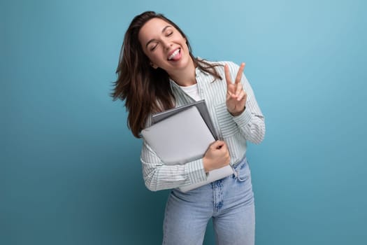 brunette young business woman in shirt with documents and laptop against background with copy pace.