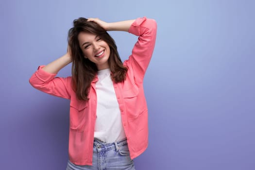 well-groomed european brunette 30s woman in pink shirt on studio background.