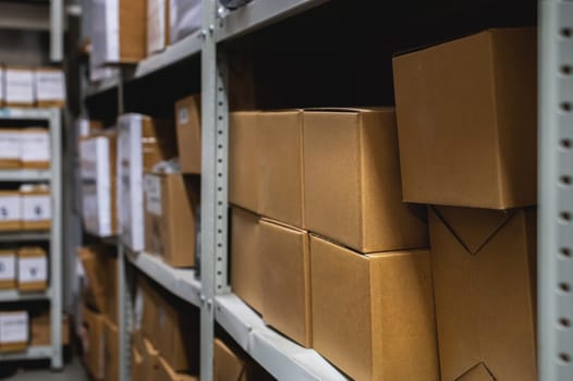 The warehouse is filled with boxes of goods placed on shelves. Commercial shelves of a store or production warehouse, blurred background, no people.