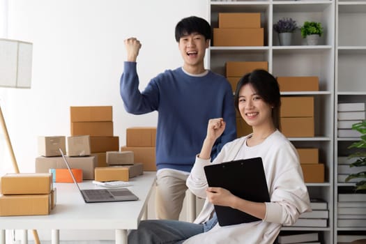 Young Asian women couples are happy together after online selling things successfully. Attractive young Asian couples online shopping while working from home on laptop.