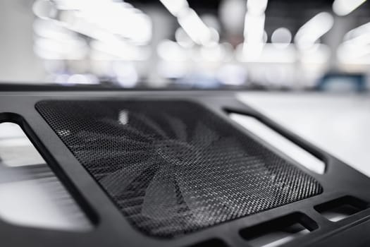 Laptop cooling pad or stand with a fan is sold on a shelf in an electronics store.