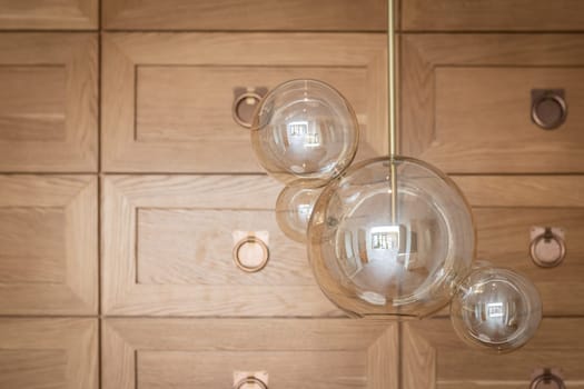 modern glass lamp chandelier close-up on the background of a wooden decorative wall.