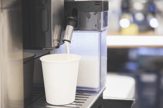 Cappuccino is poured into a white paper cup, take your coffee with you.