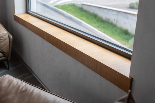 Wooden window sill near a large window in a modern interior.