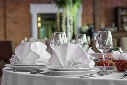 Festive table setting with white tablecloth. Decoration of the banquet table before the event.