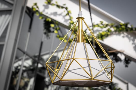 Designer garden pendant lamp hanging on the summer terrace during the day.